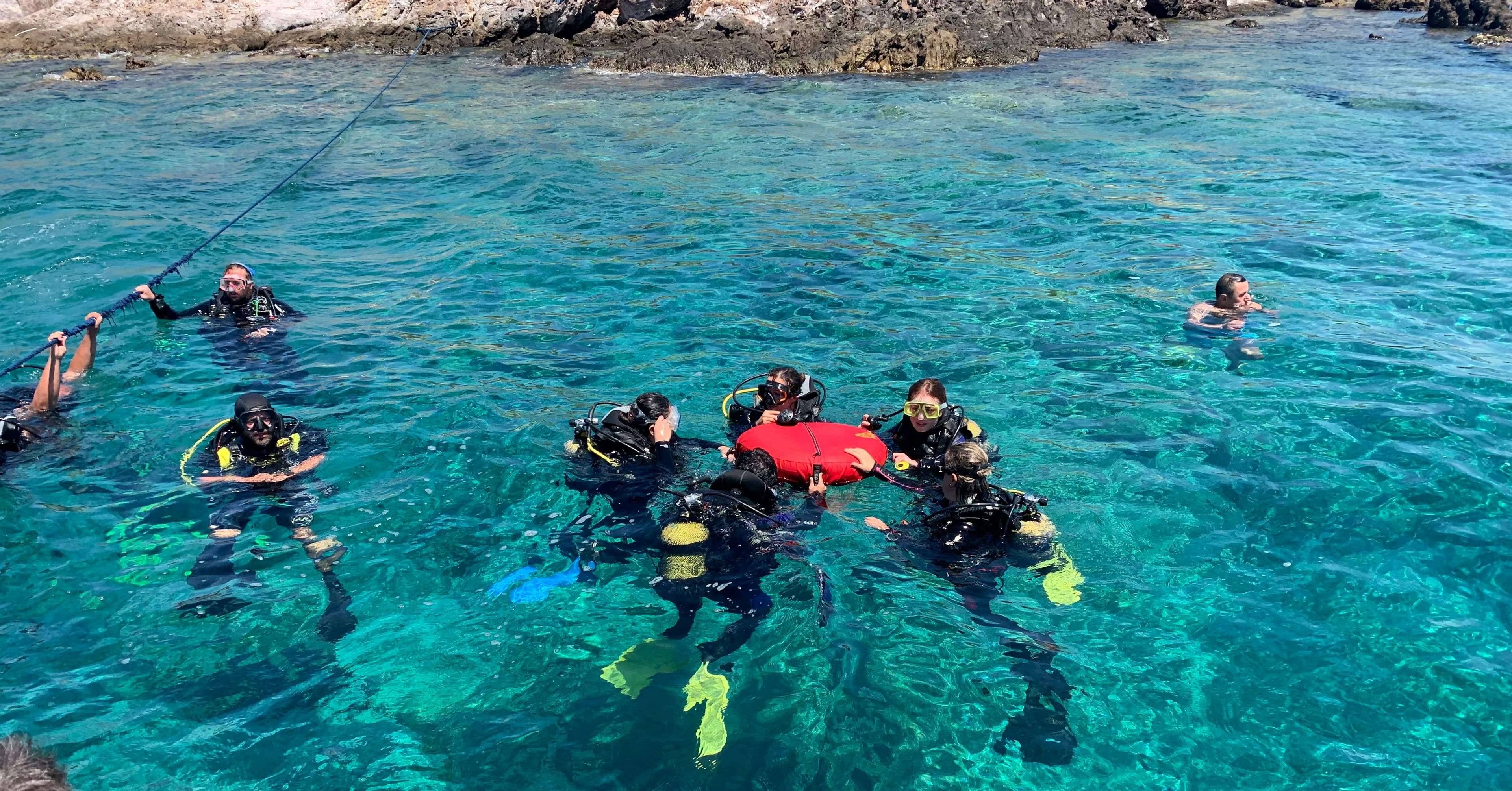 Divers grouped together in clear blue water before a dive
